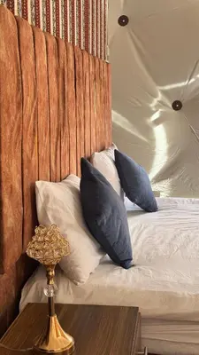 a bed with blue pillows and a wooden headboard at wadi rum Bubble lunara luxury camp in Wadi Rum