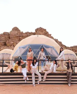 a group of people sitting on steps in front of a tent at wadi rum Bubble lunara luxury camp in Wadi Rum