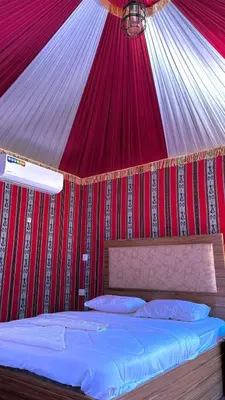 a bed in a tent with a red ceiling at wadi rum Bubble lunara luxury camp in Wadi Rum