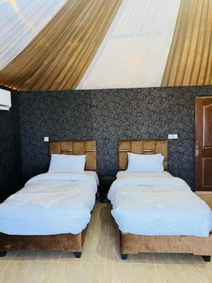 two beds sitting next to each other in a room at Rum Ronza Luxury Camp in Maḩaţţat Dīsah