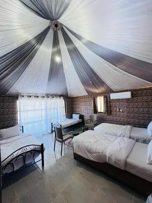 a bedroom with two beds and a tent at Rum Ronza Luxury Camp in Maḩaţţat Dīsah