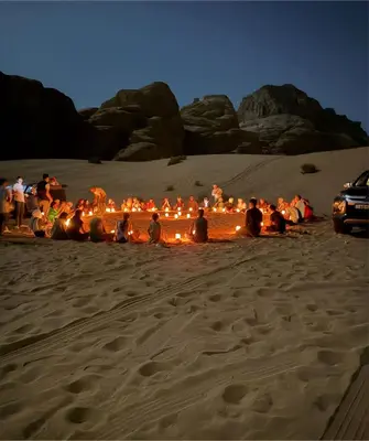 a group of people sitting in the sand at night at Mohammad rum camp in Disah