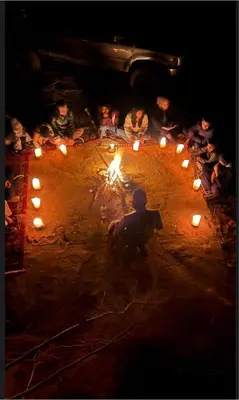 a group of people sitting around a circle with lights at Mohammad rum camp in Disah