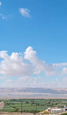 a view of a field with a blue sky and clouds at Panoramic GUESTHOUSE - OUM ALI in Aş Şāfī