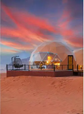 a large domed building in the desert with a sunset at Rum luxury camp hotel in Wadi Rum