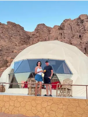 a man and woman standing in front of a tent at Rum luxury camp hotel in Wadi Rum