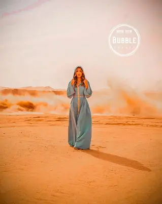 a woman in a blue dress standing in the desert at WADi RUM BUBBLE in Wadi Rum