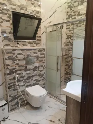 a bathroom with a toilet and a tv on the wall at شقق في عمان in Al Jafr