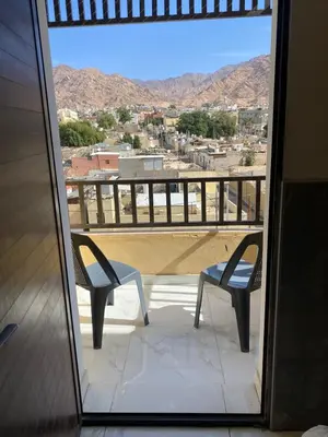 a balcony with two chairs and a view of a city at Avatar Hotel-Aqaba in Aqaba