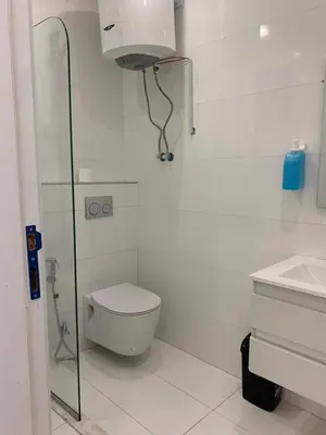 a white bathroom with a toilet and a sink at Boulevard Comfort Haven, apt with stunning veiw in Amman