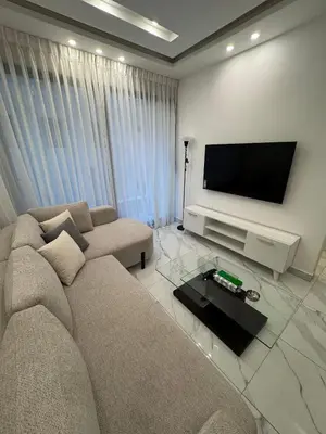 a living room with a couch and a flat screen tv at Boulevard Comfort Haven, apt with stunning veiw in Amman