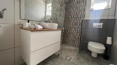 a white bathroom with a sink and a toilet at An Overlooking Rooftop in Amman in Amman
