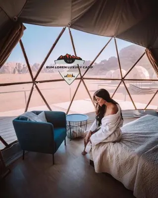 a woman sitting on a bed in a tent at RUM LOREN lUXURY CAMP in Wadi Rum
