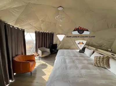 a tent with a bed and a chair in a room at RUM LOREN lUXURY CAMP in Wadi Rum