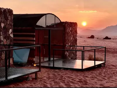 a bed in the desert with the sunset in the background at Starlit Wadi Rum camp in Wadi Rum