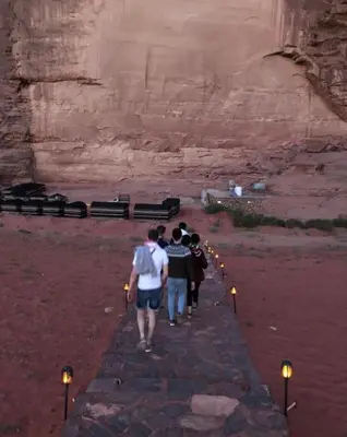 a group of people walking through a canyon with lights at Starlit Wadi Rum camp in Wadi Rum