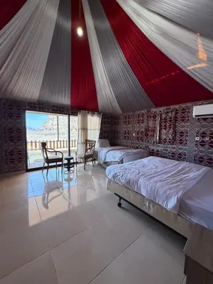 a bedroom with two beds and a table in a tent at Dune Horizon Camp in Wadi Rum