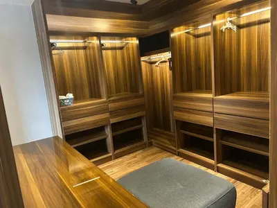 a walk in shower with wooden cabinets and a bench in a room at Elegant & Cozy Apartment in Heart of Amman in Amman
