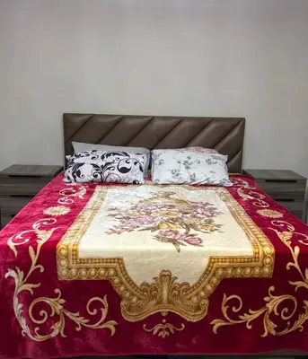 a bed with a red and gold blanket and pillows at Ash Shawbak Apartment in Umm Şawwānah