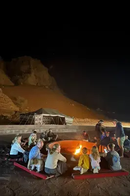people sitting around a fire on the beach at night at Luxury Mars Camp in Wadi Rum