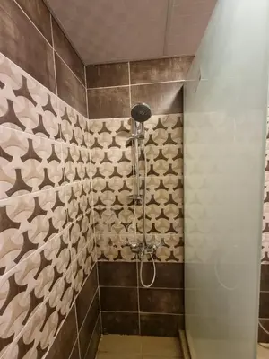 a bathroom with a shower with brown and white tiles at Luxury Mars Camp in Wadi Rum