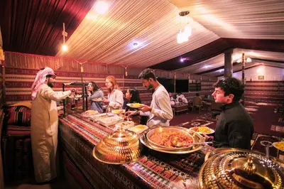 a group of people standing around a buffet line with food at Magic Cave Night Tours in Wadi Rum