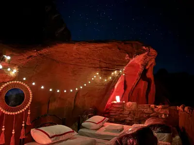 a room with beds in a cave with lights at Magic Cave Night Tours in Wadi Rum