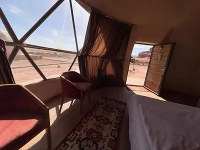 a room with two chairs and a window with a view of the desert at Wadi Rum Desert Wonders Camp in Disah