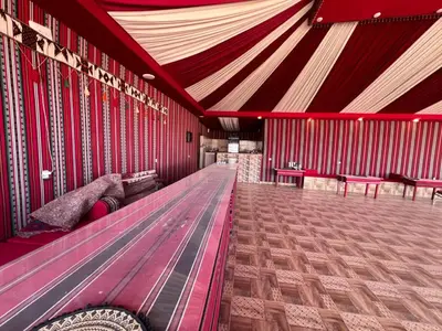 a room with red walls and a long wooden bench at Wadi Rum Desert Wonders Camp in Disah