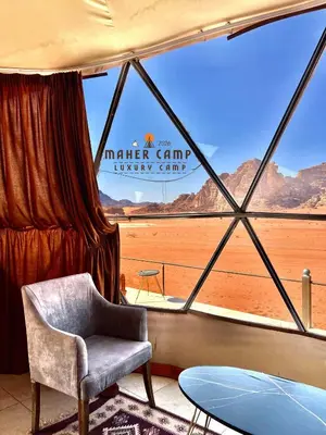 a room with a chair and a view of the desert at Wadi rum maher luxury camp in Wadi Rum
