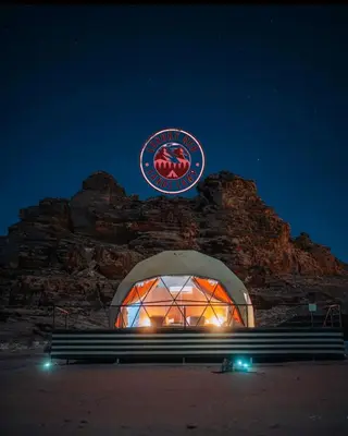 a building with a sign and a bench at night at RUM lUXURY MM SANDS CAMP in Wadi Rum