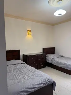 a bedroom with two beds and a light on the wall at Deir Ghbar apartment 116 in Amman