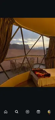 a bed in a tent with a view of the desert at Golden Camp in Wadi Rum
