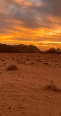 a sunset in the desert with mountains in the background at Golden Camp in Wadi Rum