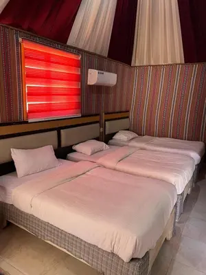 two beds in a room with a red window at RUM FIRAS lUXURY CAMP in Wadi Rum
