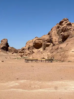 two benches sitting in the desert near a mountain at RUM FIRAS lUXURY CAMP in Wadi Rum