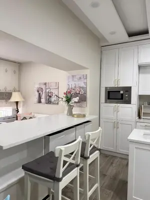 a kitchen with white cabinets and white counter chairs at Modern Apartment, Untouched & Ready to Stay in Amman