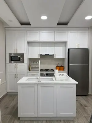 a kitchen with white cabinets and a black refrigerator at Modern Apartment, Untouched & Ready to Stay in Amman
