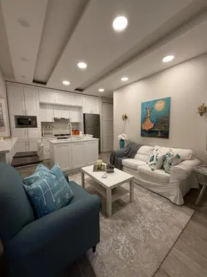 a living room with two couches and a kitchen at Modern Apartment, Untouched & Ready to Stay in Amman