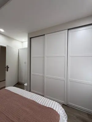 a bedroom with white closet doors and a bed at Modern Apartment, Untouched & Ready to Stay in Amman