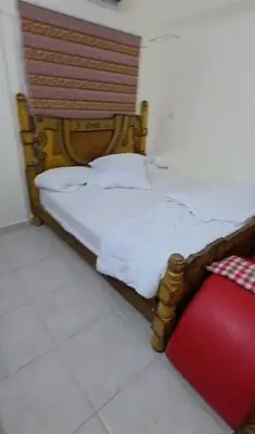 a bed with a wooden headboard and a red pillow at عبدالرحمن الشطناوي2 in Aqaba