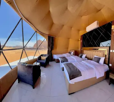 a bedroom with four beds and a large window at TAJ luxury Camp in Wadi Rum