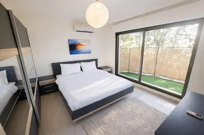 a bedroom with a bed and a large window at Abdoun Grand Family Apartment in Amman