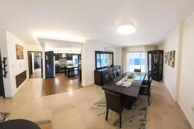 a dining room and living room with a table and chairs at Abdoun Grand Family Apartment in Amman