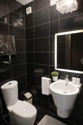 a black tiled bathroom with a toilet and a sink at Abdoun Grand Family Apartment in Amman