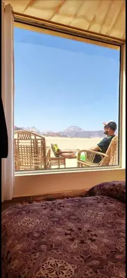 a person sitting in a chair looking out a window at the beach at Essam camb in Disah