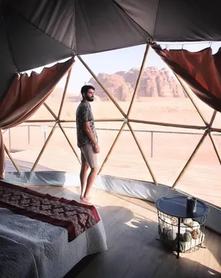 a man standing in a tent with a view of the desert at rum magic luxury camp in Wadi Rum