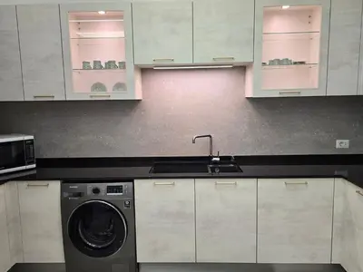 a kitchen with white cabinets and a washing machine at Two-bedroom family friendly modern apartment in Amman