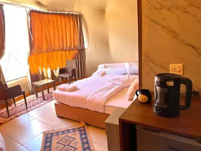 a bedroom with a bed and a table with a mirror at Golden Dunes Camp Wadi Rum in Wadi Rum