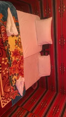 a bed with white pillows on top of it at Enad wadirum camp in Wadi Rum